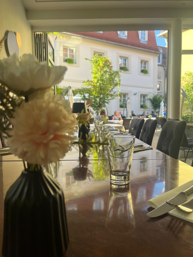 Ein Tisch in einem Restaurant, dekoriert mit frischen Blumen und eleganten Vasen, sorgt für eine gemütliche Stimmung.